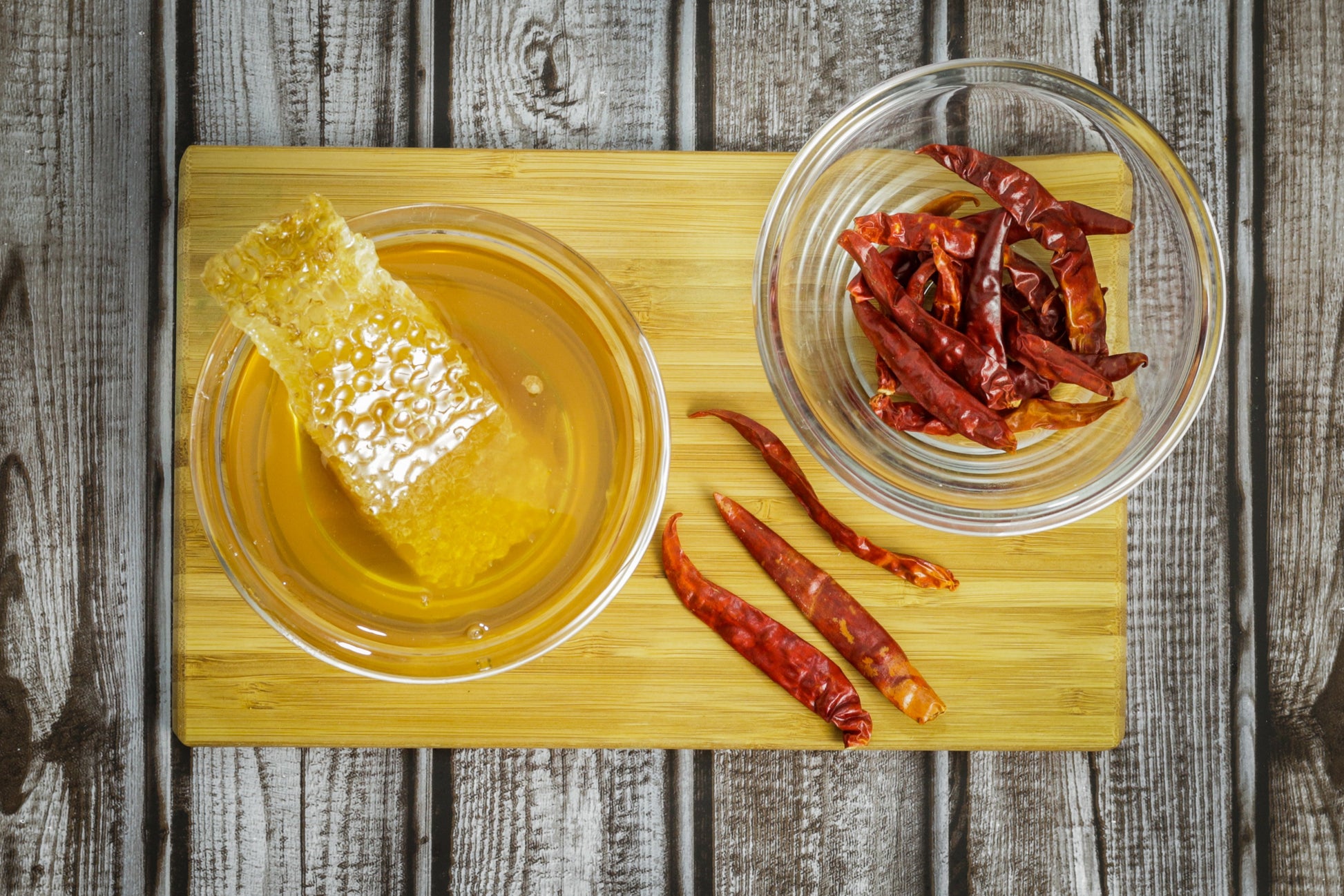Honey In Bowl with Honeycomb next to Bowl of Red Cayenne Peppers