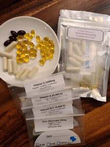 Picture of 4 Day Power 4 Immune Boosting Supplement Pack with vitamins separated into daily doses in small bags for convenience, a bowl displaying vitamins, and the full package laid out in a display on a wooden countertop
