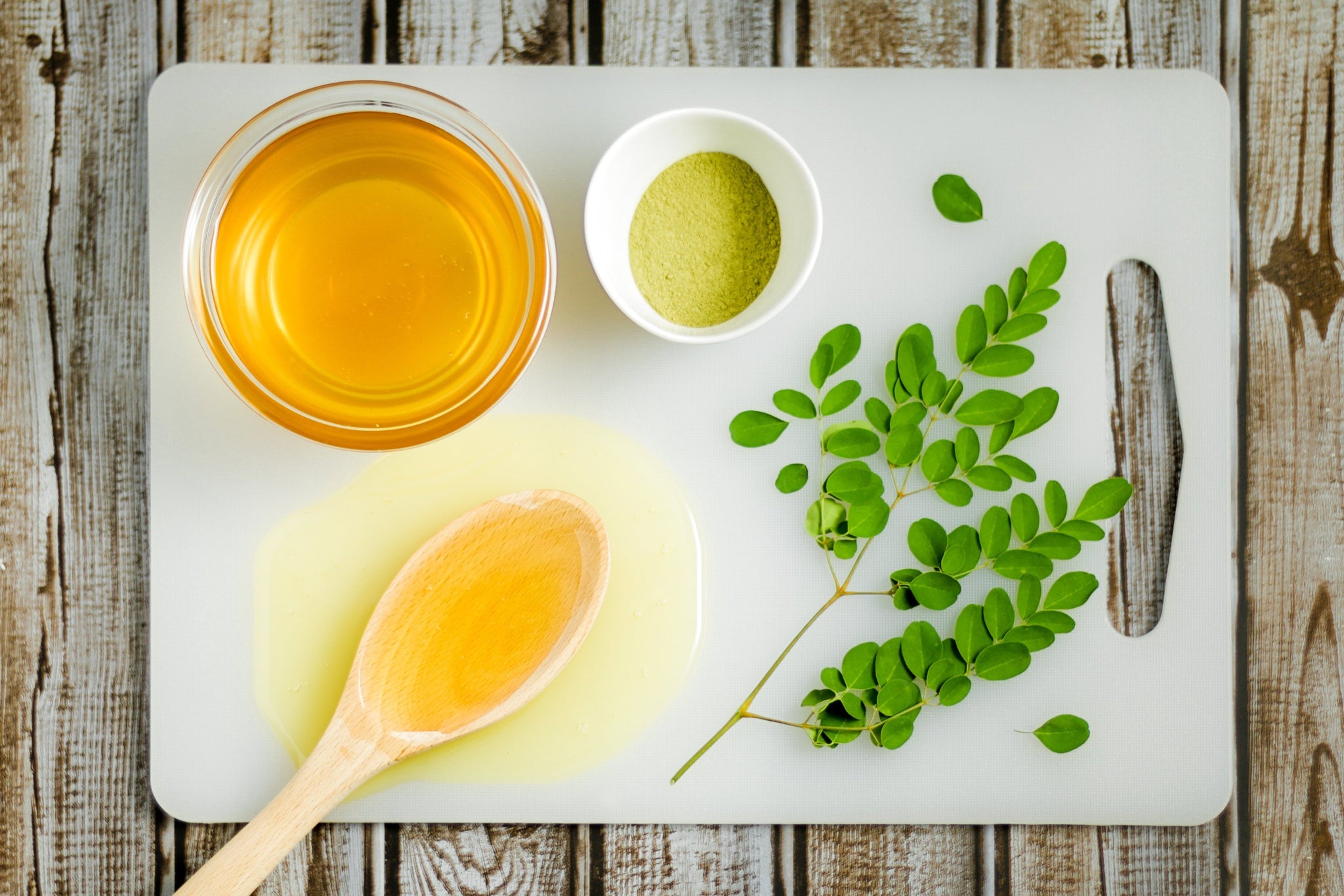 Honey In Bowl on Cutting Board with Moringa Beside it