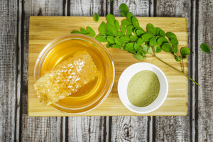 Honey In Bowl on Cutting Board with fresh and Powdered Moringa Beside it
