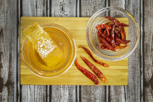 Load image into Gallery viewer, Honey In Bowl with Honeycomb next to Bowl of Red Cayenne Peppers 
