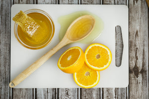 Raw Local Florida Orange Blossom Honey with honey-comb on cutting board with orange slices